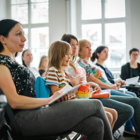 Personen sitzen in einem Vortragsraum und hören zu.