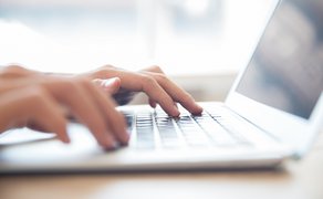 Nahaufnahme von einer Person, die an einem Laptop arbeitet