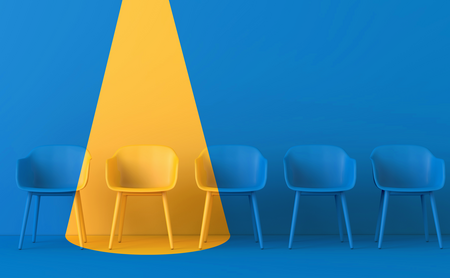 Bild von leeren Stühlen mit einem Stuhl in gelbem Scheinwerferlicht