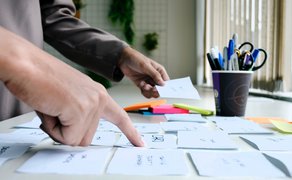 Bild von Händen, die Notizblätter sortieren