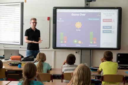 Bild von einem Lehrer, der die Ergebnisse von einem Kahoot-Spiel mit seiner Klasse bespricht
