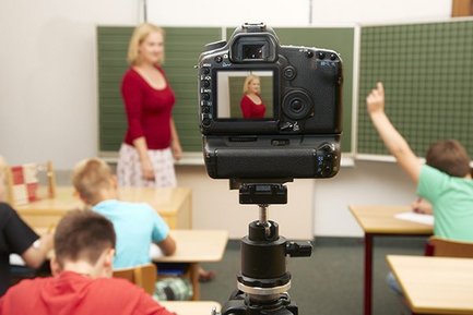 Bild einer digitalen Kamera, die eine Leherin im Klassenzimmer aufnimmt